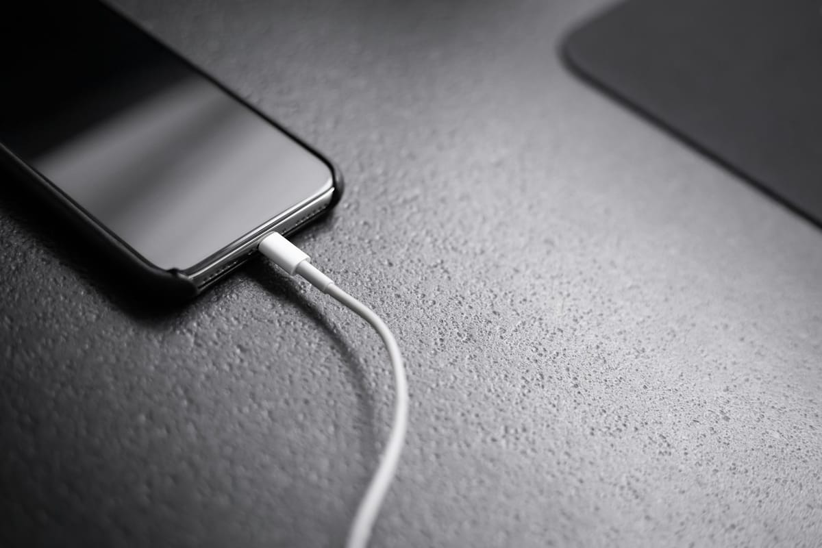 A black smartphone with a charging cable plugged in