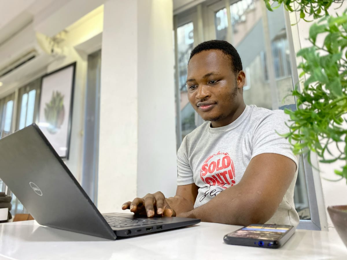 A smiling young man working on a laptop