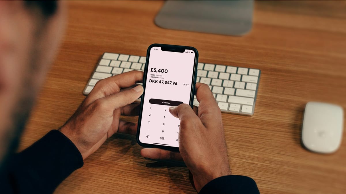 A man checking a payment amount on his phone at a desk