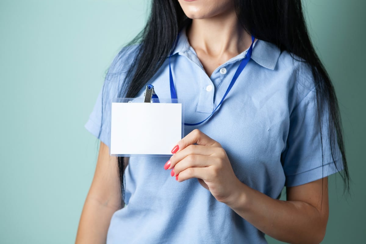 A woman holding up a blank ID card on a lanyard