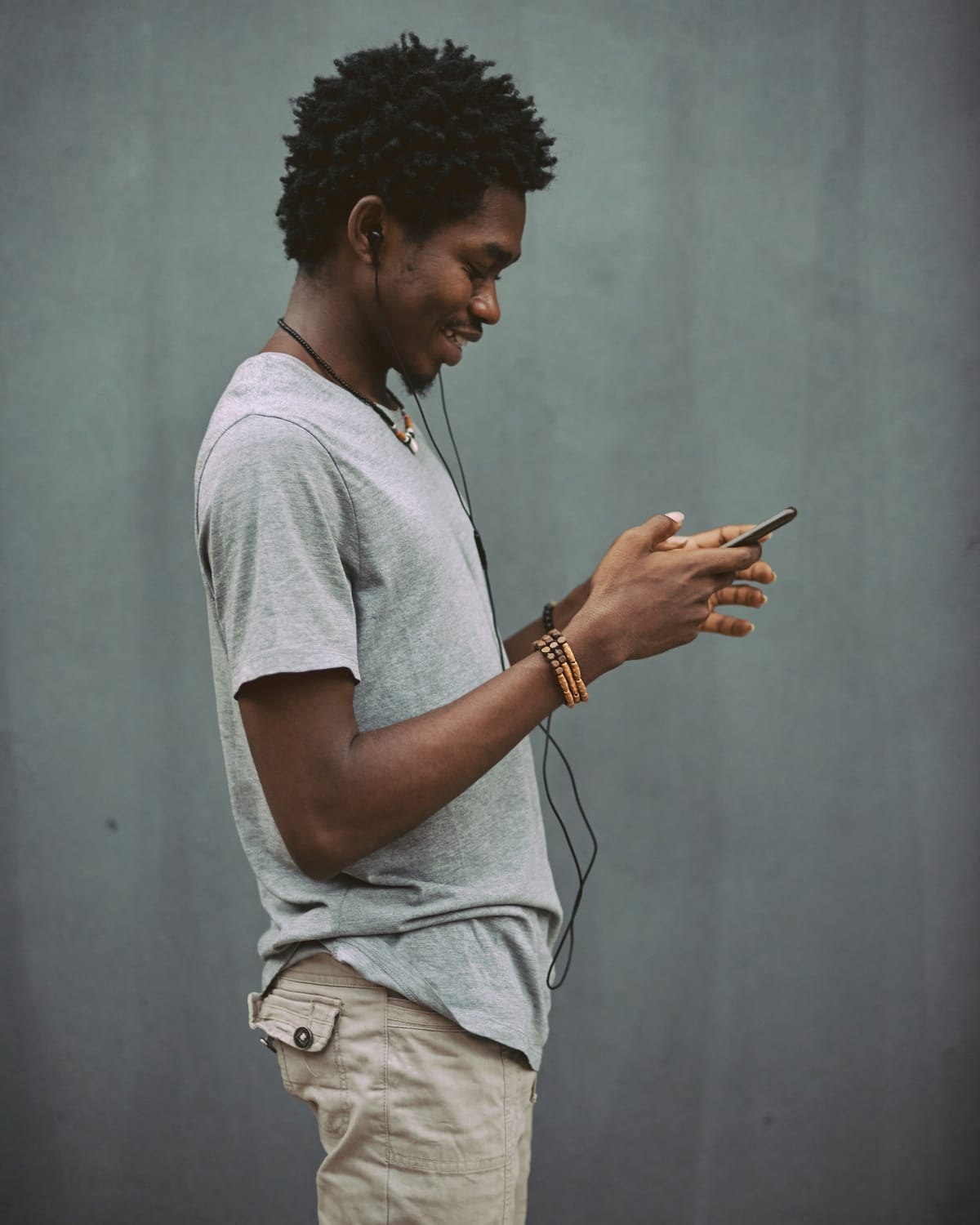 A man in a white T-shirt holding a smartphone