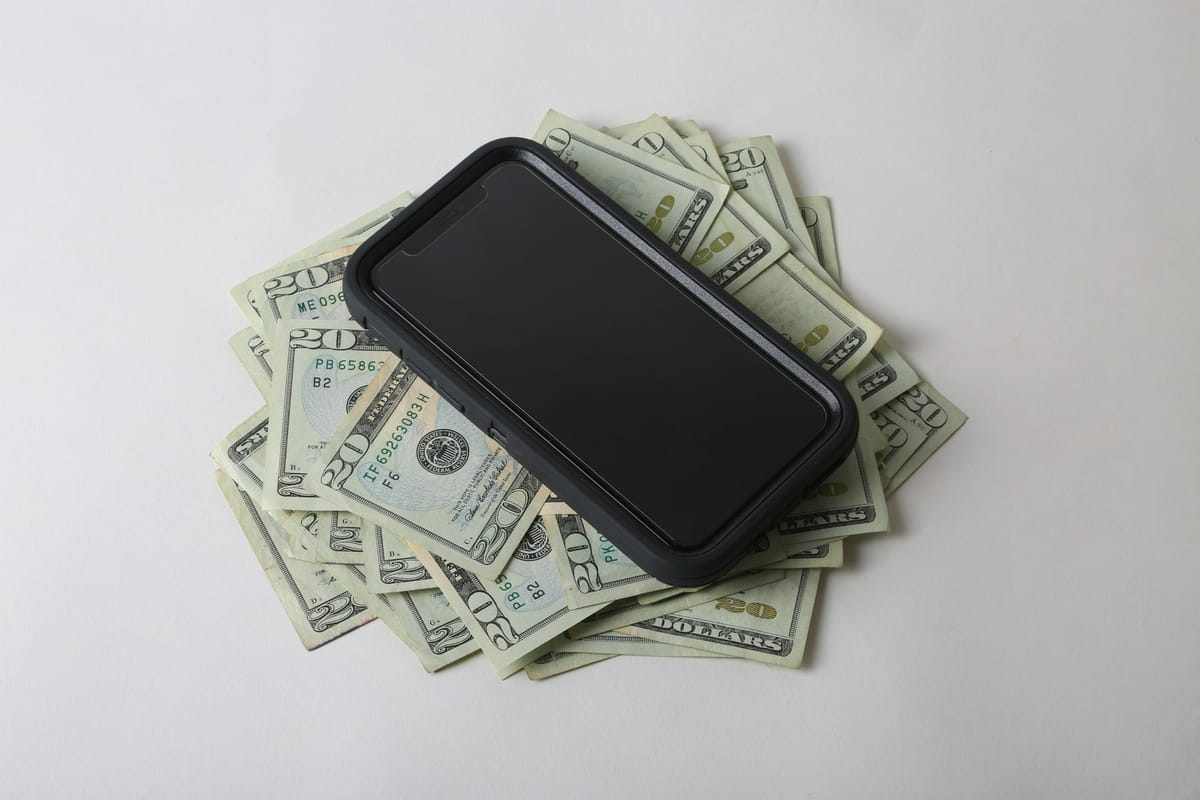 A smartphone lying on a pile of banknotes
