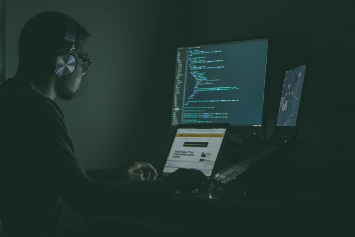 A person working at several screens in the dark