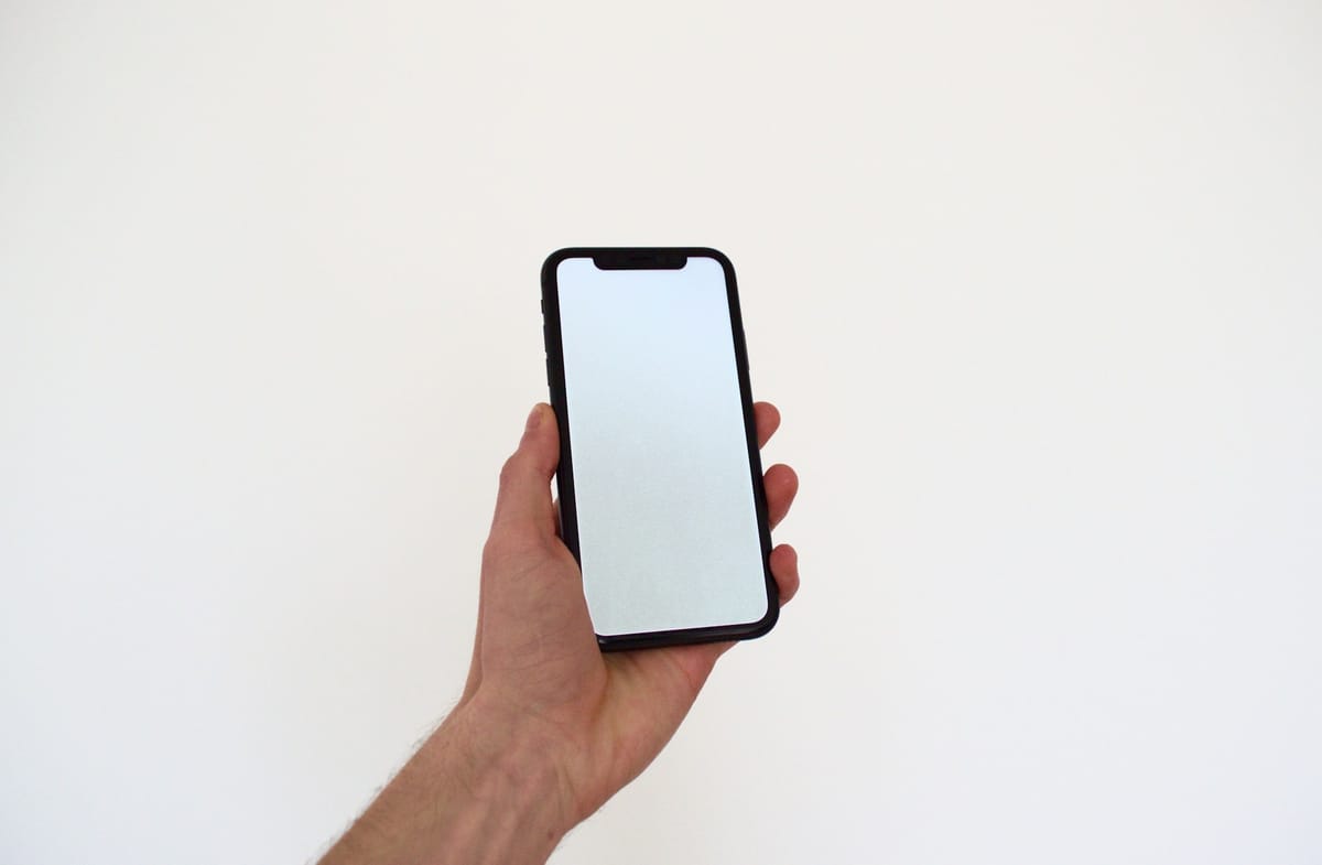 A hand holding an iPhone against a white background
