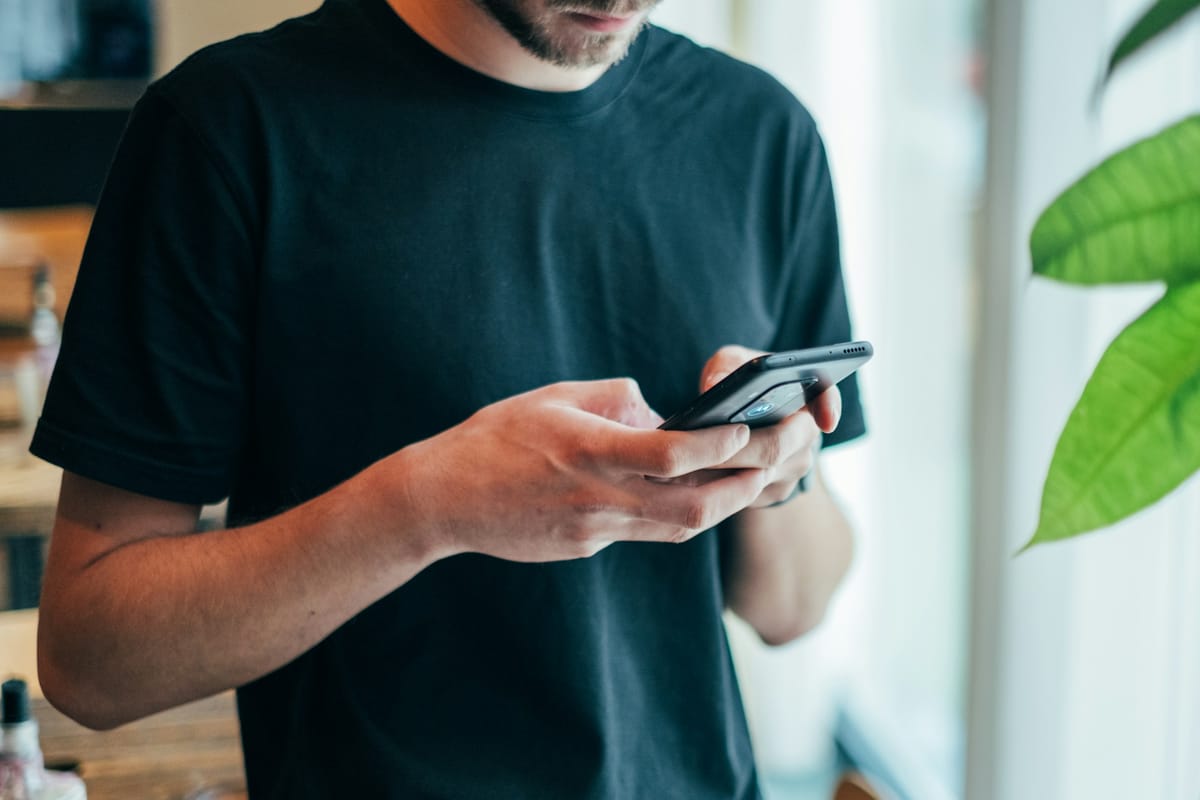 A man in a black T-shirt using a smartphone