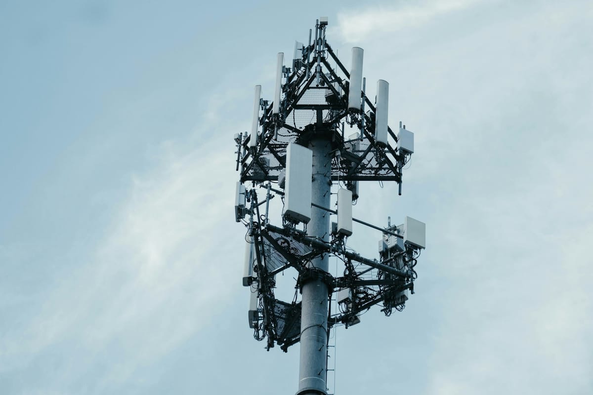A mobile network antenna tower against a pale sky