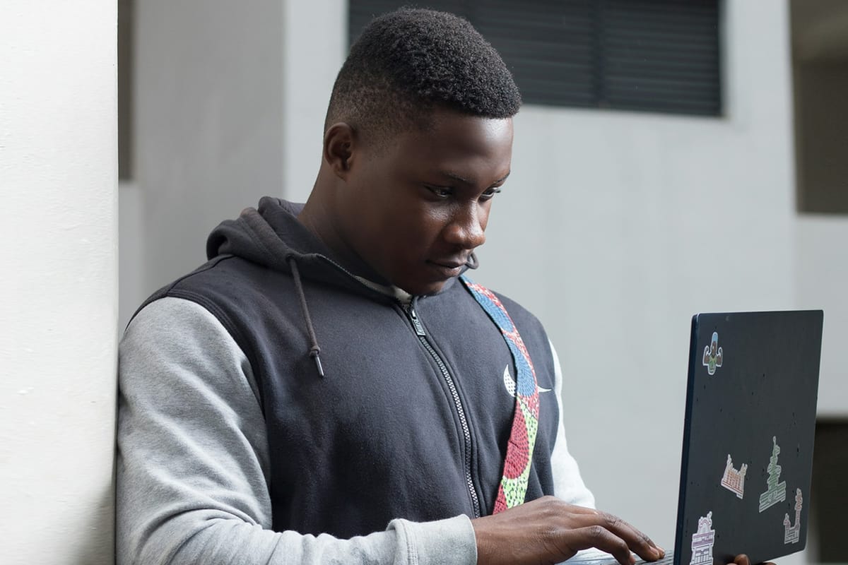 A young man holding a laptop in one hand