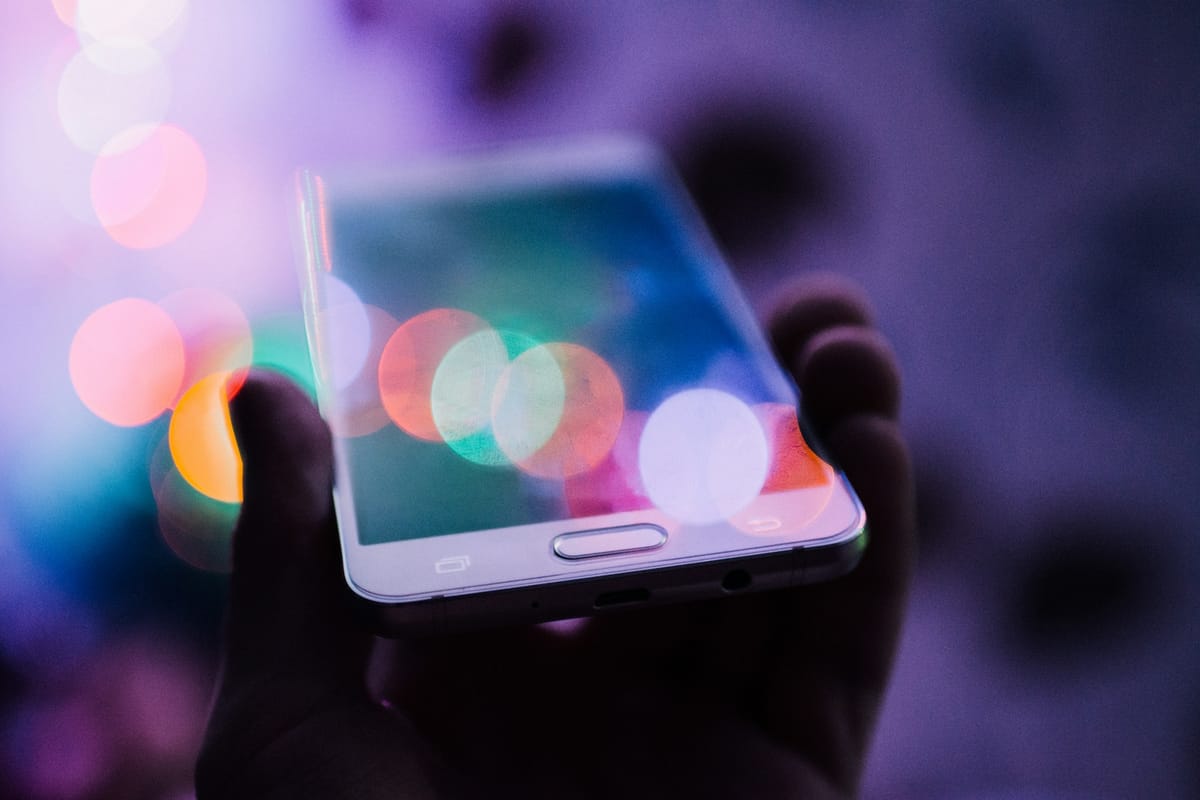 A hand holding a smartphone with colourful lights