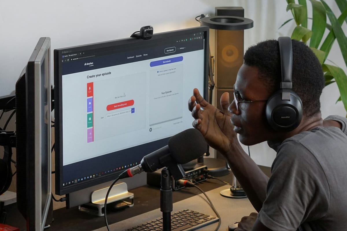 A man in headphones working at a computer with a microphone
