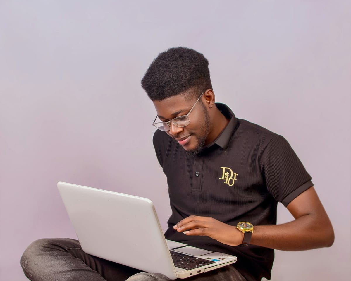 A young man sitting with a laptop on his lap