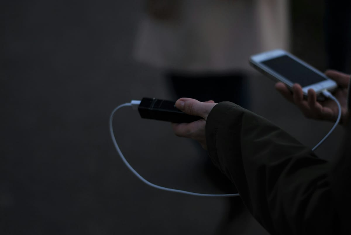 A person holding a mobile phone and a charger