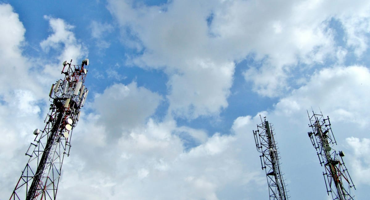 Several cell towers under a cloudy blue sky