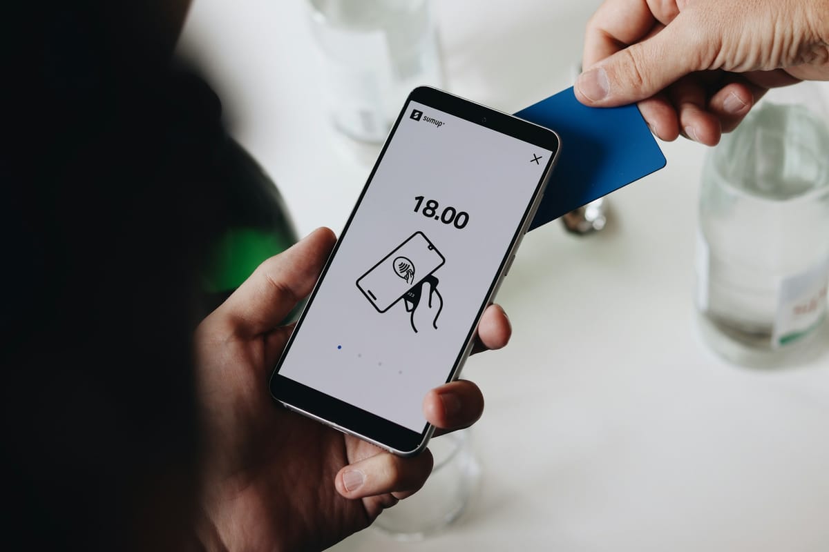 A hand holding a phone during a card payment