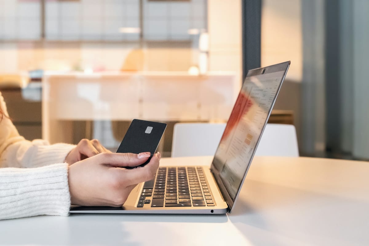 A person holding a bank card in front of a laptop
