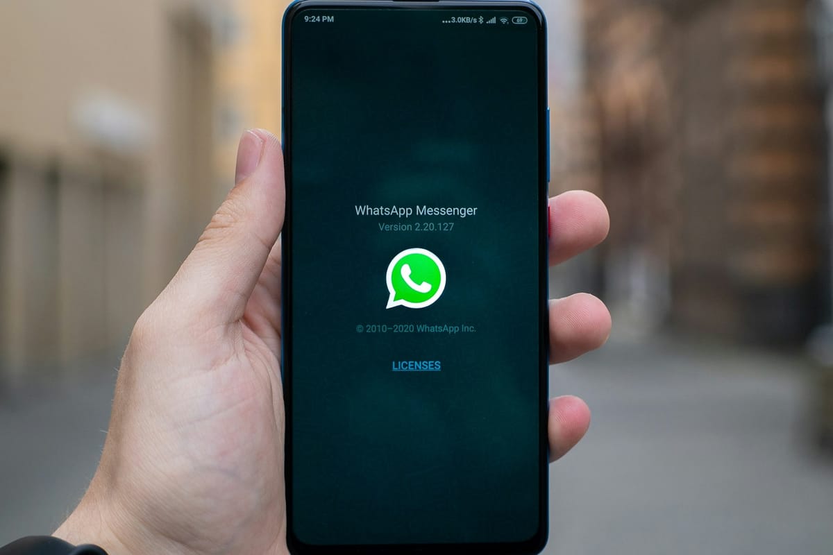 A hand holding a phone with WhatsApp loading