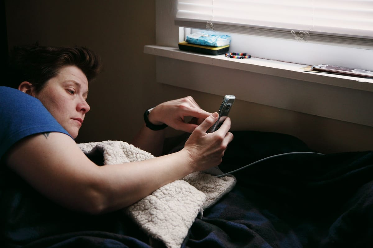 A person lying in bed using a phone that is charging