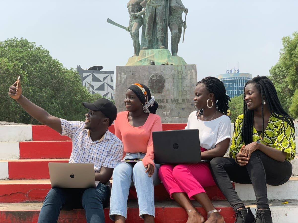 Young people sitting outdoors with laptops and phones