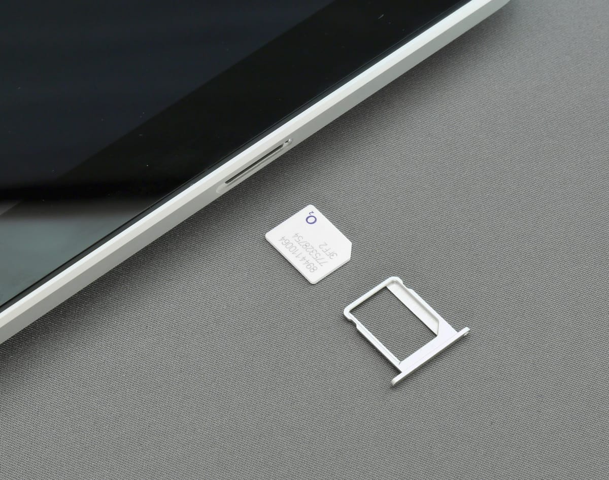A SIM card and SIM tray next to a phone