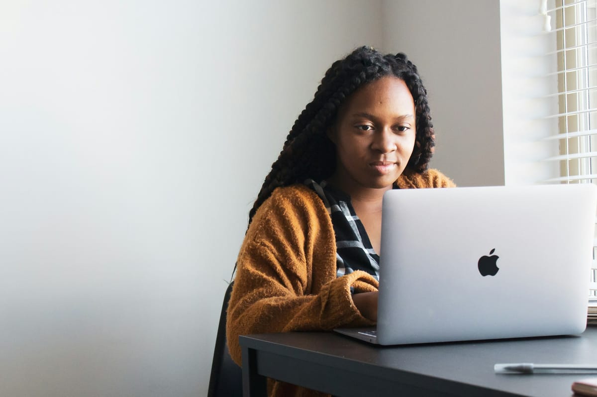 A woman with braids working on a laptop