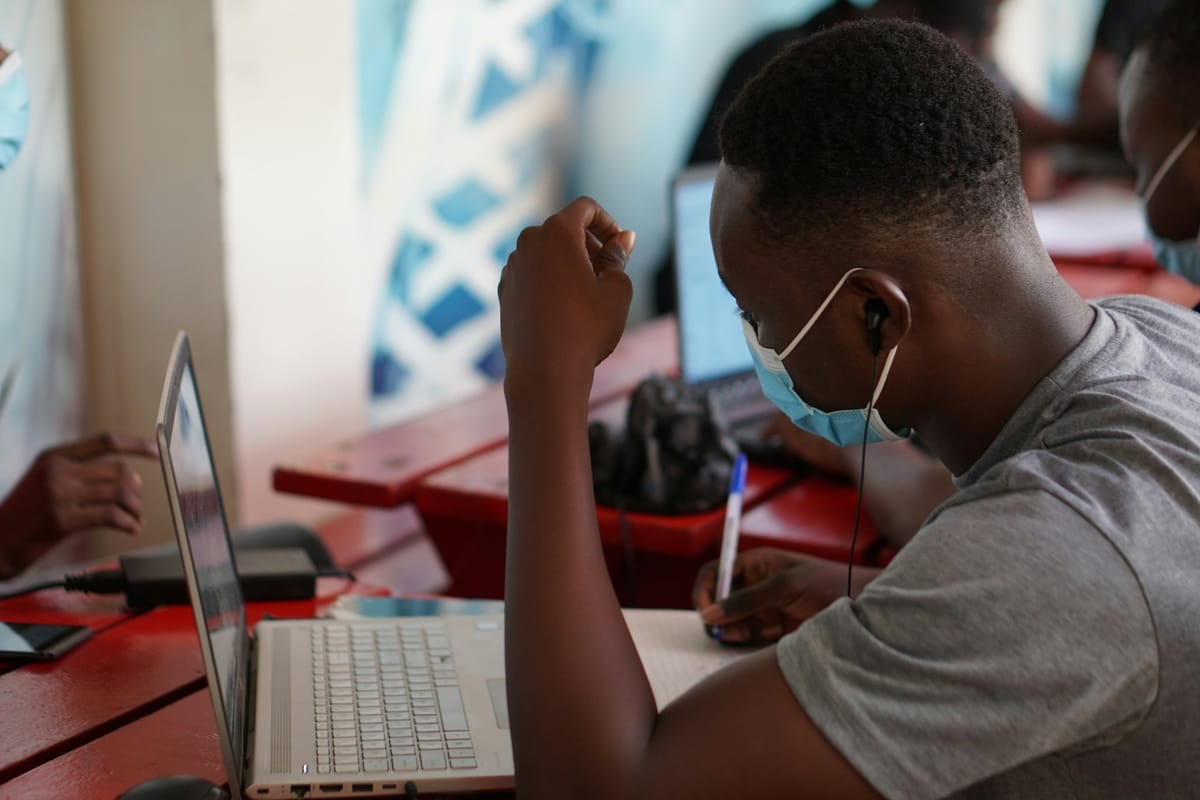A young man with earbuds working on a laptop