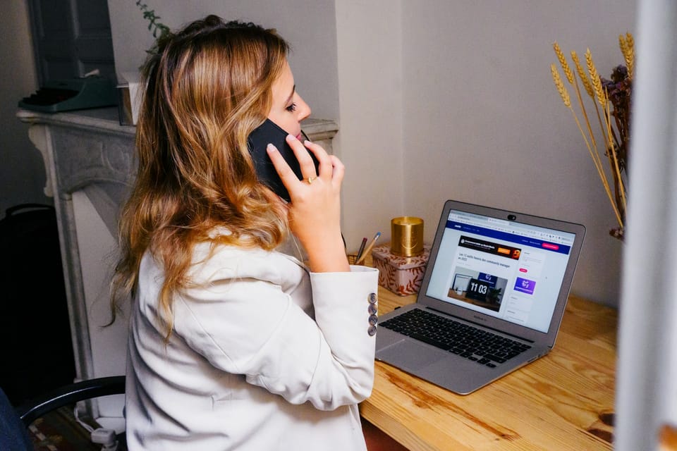 A woman on a phone call at a desk with a laptop