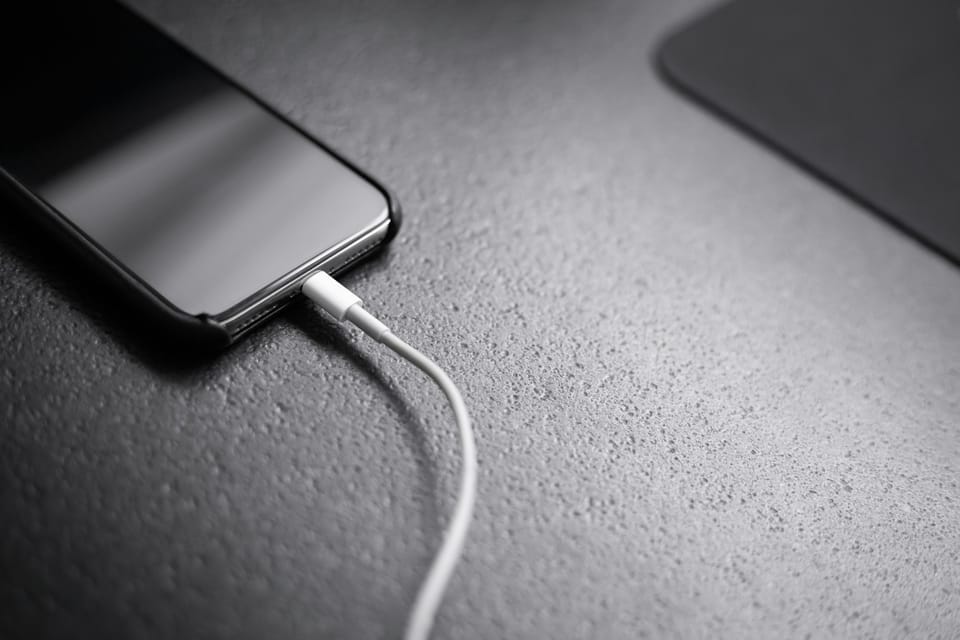 A black smartphone with a charging cable plugged in