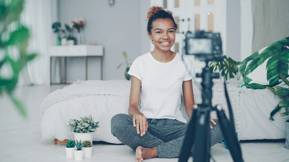 A young woman filming herself with a camera at home