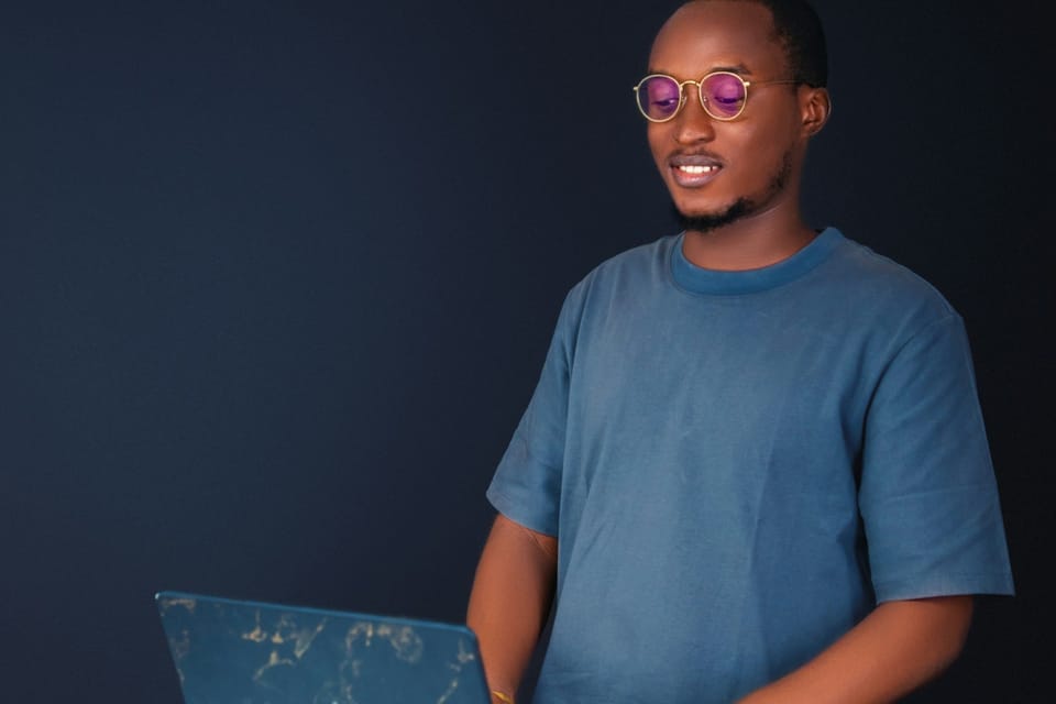 A smiling man in glasses working on a laptop