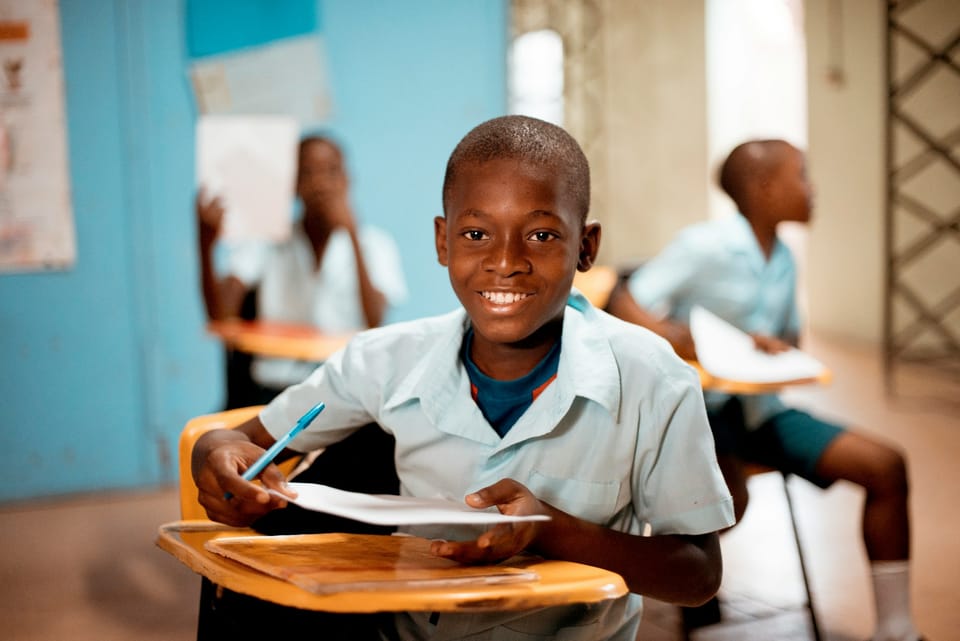 A smiling schoolboy writing at his desk