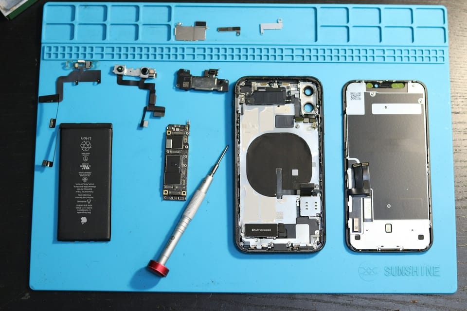 iPhone parts and battery laid out on a repair mat
