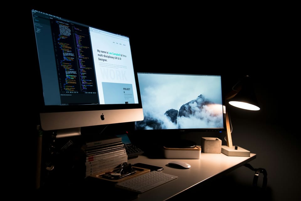 A computer setup with two screens in a dark room