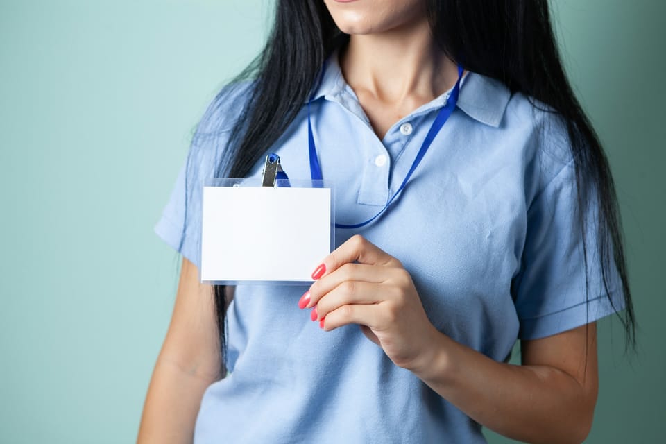 A woman holding up a blank ID card on a lanyard