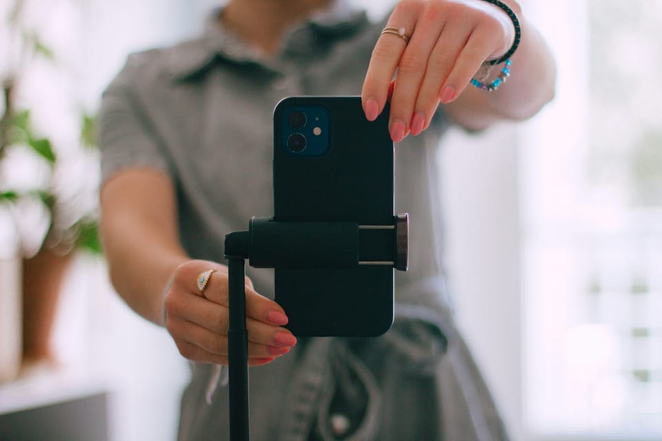A person setting a phone on a tripod to record