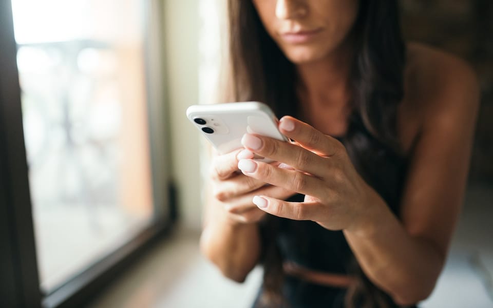 A woman using her smartphone by a window