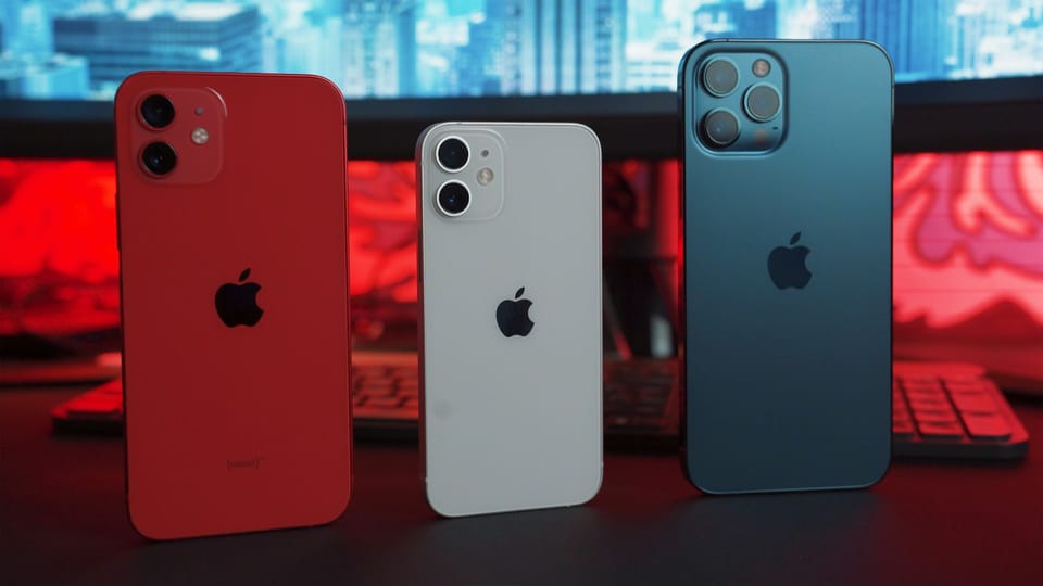 Three smartphones in red, white and blue on a desk