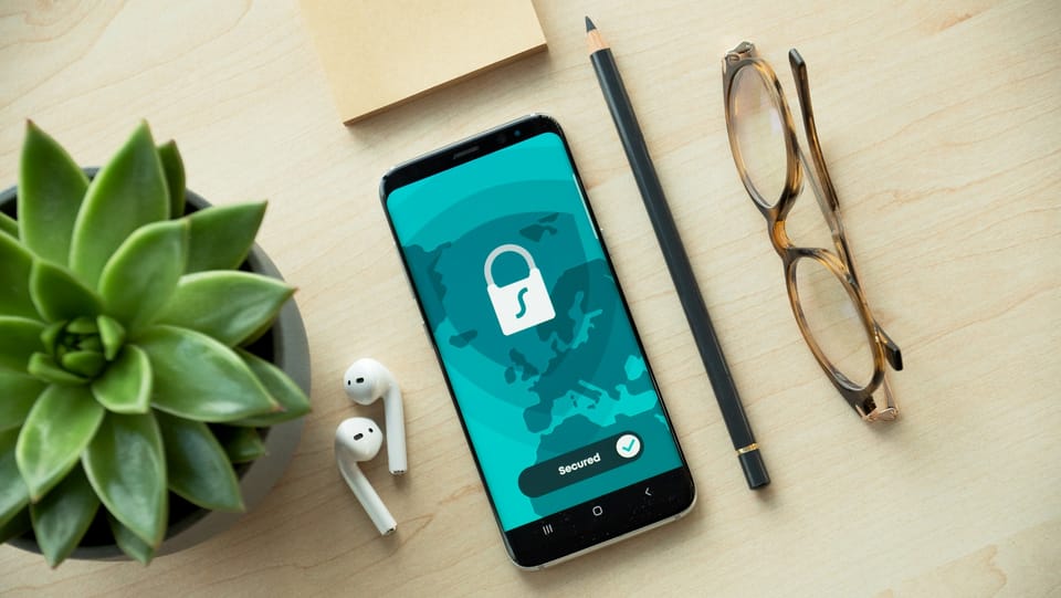 A smartphone showing a security lock icon on a wooden desk