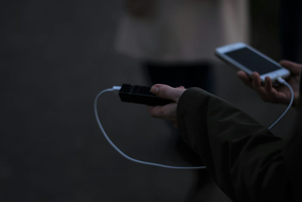 A person holding a mobile phone and a charger