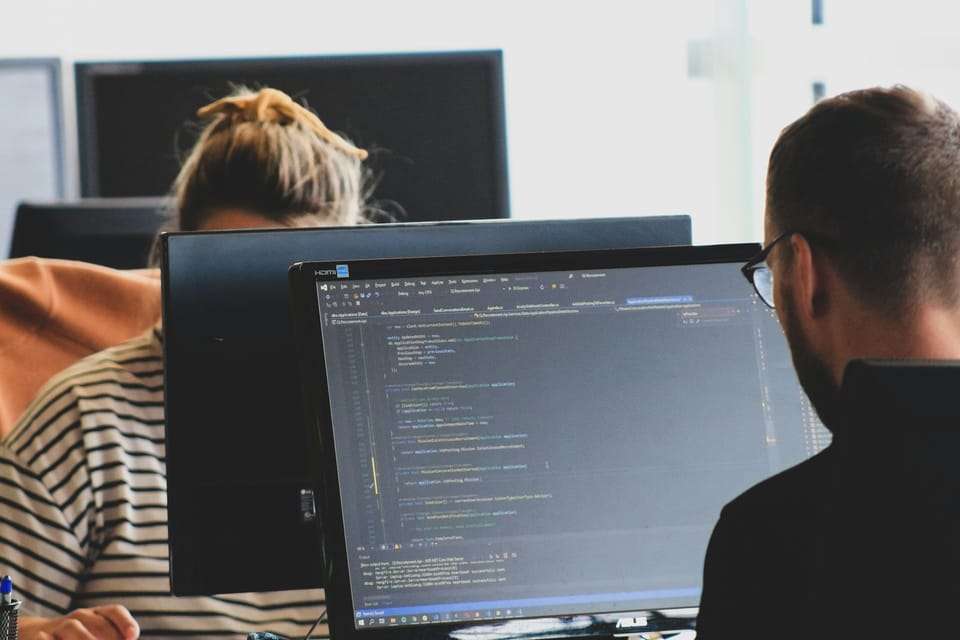 Two people writing code at computer monitors in an office