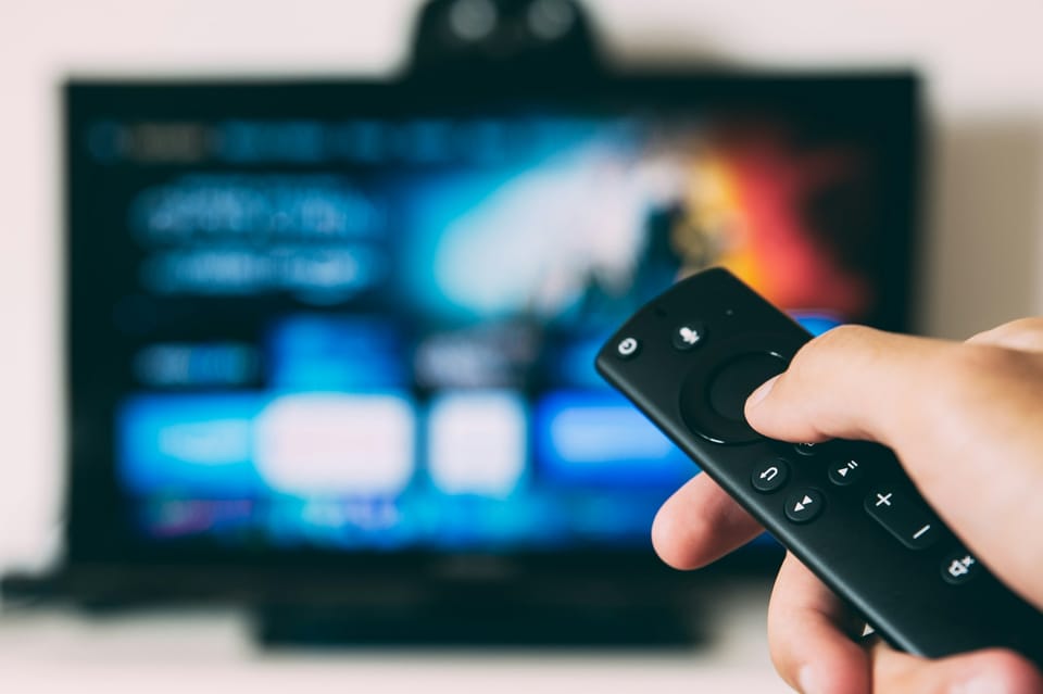 A hand pointing a remote at a television