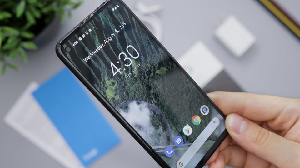 A hand holding an Android smartphone above a desk