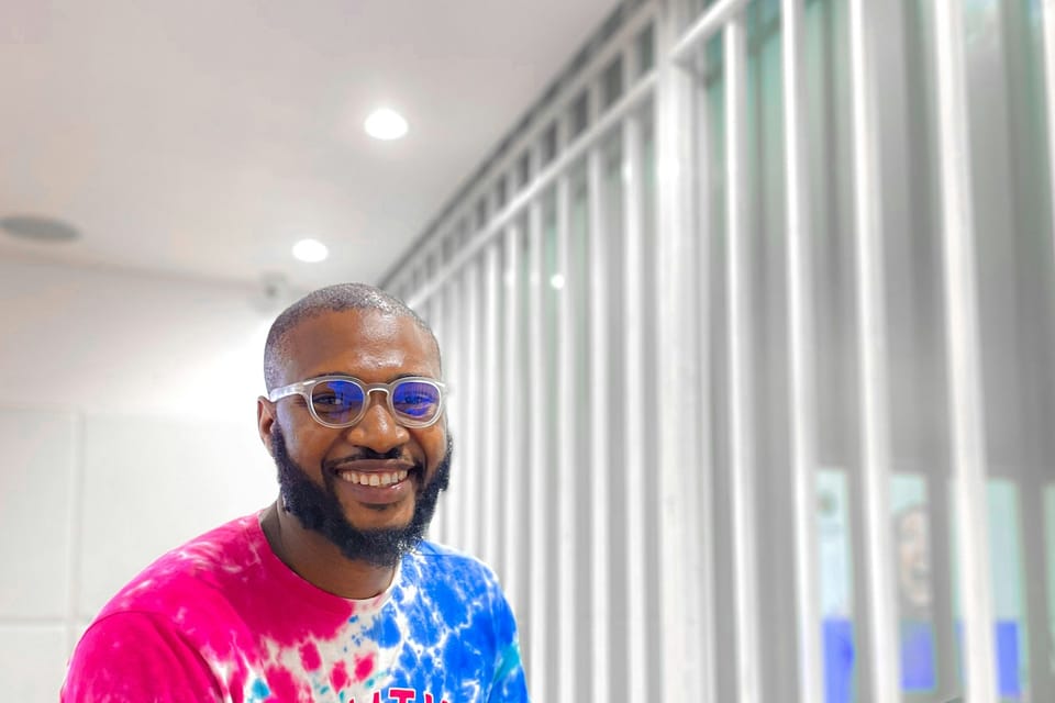 A smiling man working on a laptop in an office