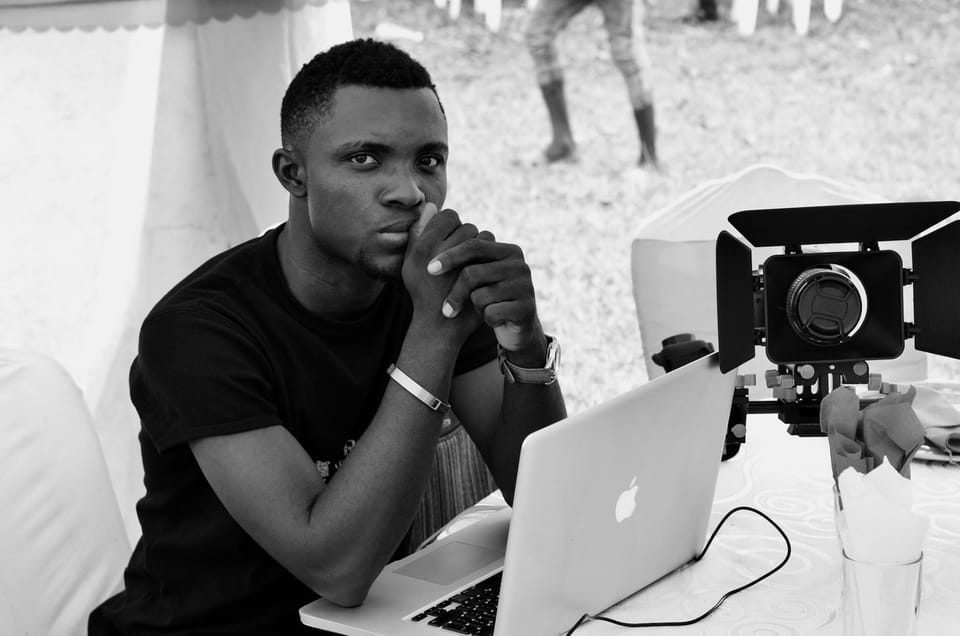 A young man at a laptop beside a video camera