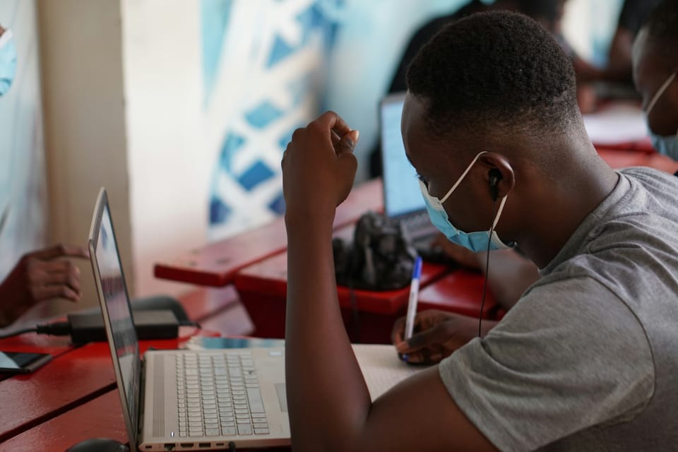 A young man with earbuds working on a laptop