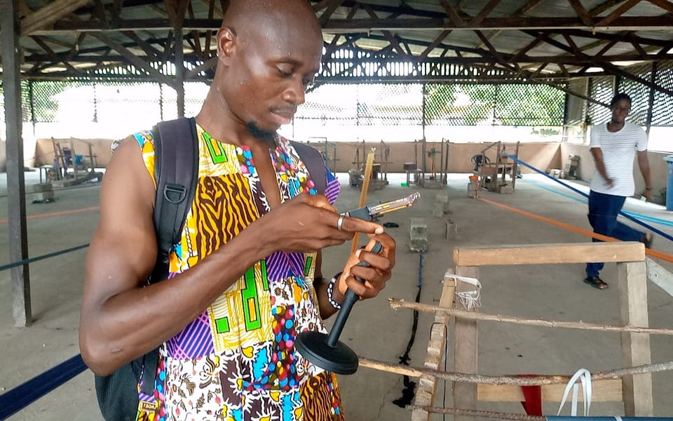 A man in a colourful African print shirt using his phone